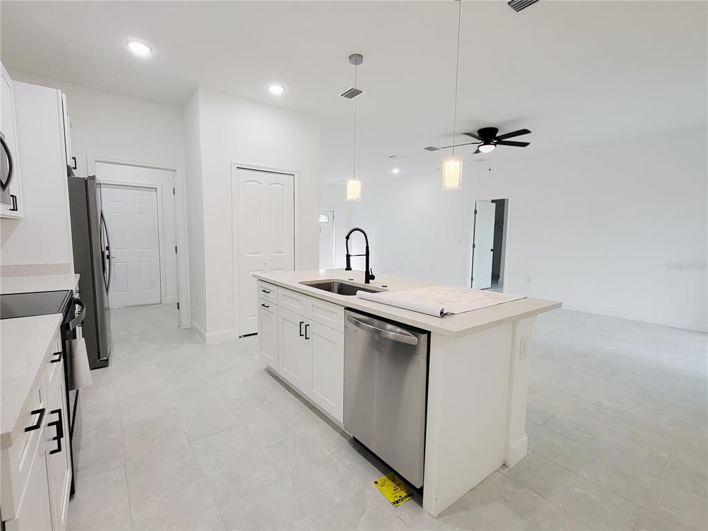 A modern kitchen features white cabinets, a central island with a dishwasher, and tile flooring — 415 TONKLIN ROAD SW, PALM BAY, FL