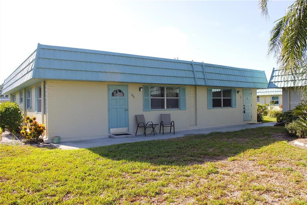 A single-story building with light yellow walls, a blue mansard roof, and two front doors — 101 CAMBRIDGE TRAIL UNIT 194, SUN CITY CENTER, FL