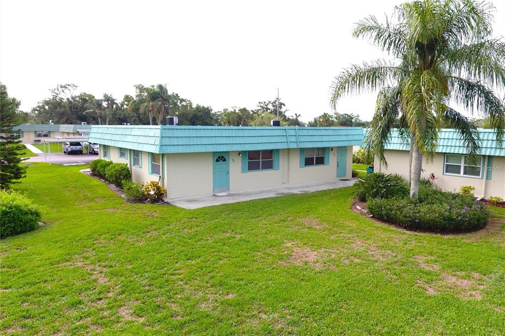 An exterior view of a single-story apartment building with a teal roof and doors — 101 CAMBRIDGE TRAIL UNIT 194, SUN CITY CENTER, FL