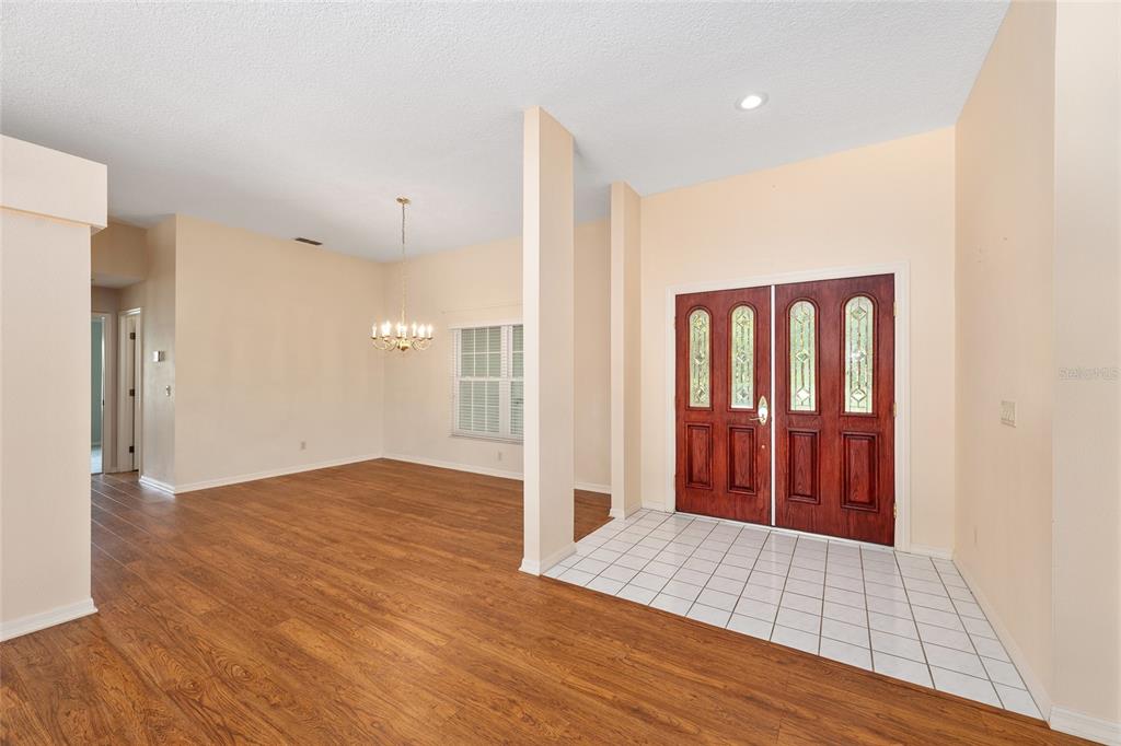 An entryway with a tiled floor leads into a dining area with wood-look flooring — 4611 N RUSHMORE LOOP, BEVERLY HILLS, FL