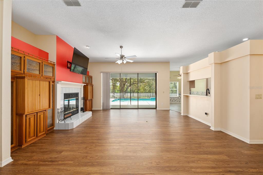 A spacious living room features wood-look flooring, a red accent wall, fireplace, and sliding doors — 4611 N RUSHMORE LOOP, BEVERLY HILLS, FL
