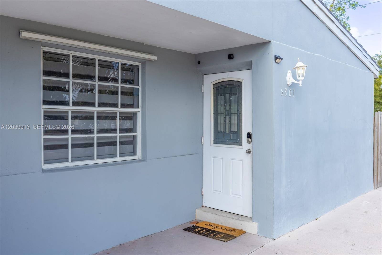 A light blue exterior wall features a white front door and a multi-pane window — 6801 Park St # 6801, Hollywood FL 33024, HOLLYWOOD, FL