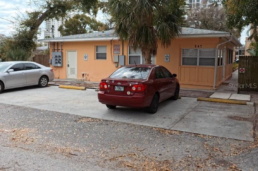 A single-story peach-colored building with two parked cars in a concrete driveway — 247 6TH AVENUE N, ST PETERSBURG, FL