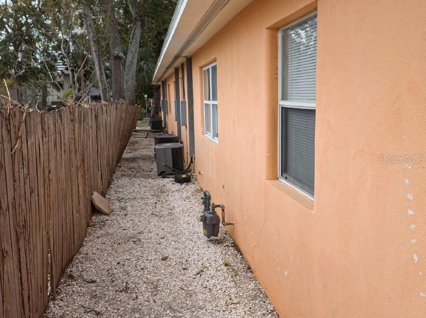 The exterior side of a peach-colored building features a gravel path, fence, and HVAC units — 247 6TH AVENUE N, ST PETERSBURG, FL