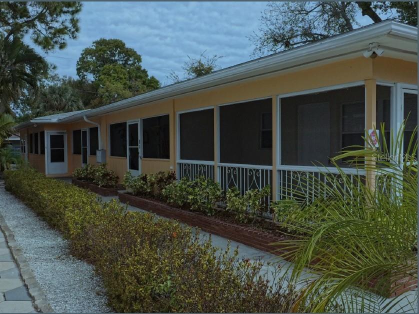 A long, single-story peach-colored house features a screened-in porch and a brick-bordered garden bed — 247 6TH AVENUE N, ST PETERSBURG, FL