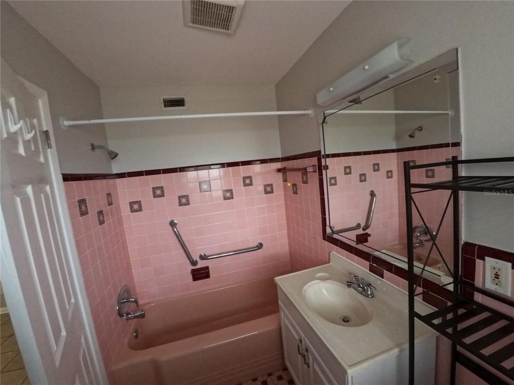 A bathroom features a pink bathtub, matching pink wall tiles, and a white vanity — 247 6TH AVENUE N, ST PETERSBURG, FL