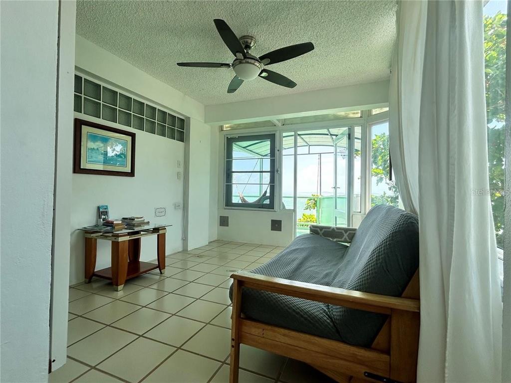 A sunroom features tile flooring, a ceiling fan, a futon, and a view of greenery — 111 FIDENCIO DE JESUS, FAJARDO, PR