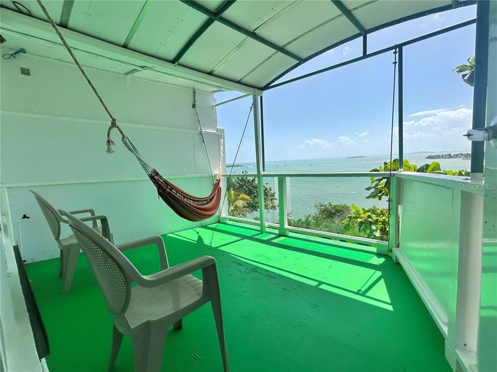 A covered balcony features a hammock, two plastic chairs, and a view of the ocean — 111 FIDENCIO DE JESUS, FAJARDO, PR