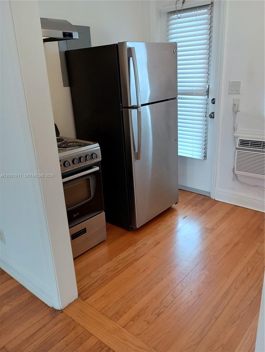 A kitchen features a stainless steel refrigerator, a small stove, and hardwood flooring — 535 74 # 11, Miami Beach FL 33141, MIAMI BEACH, FL