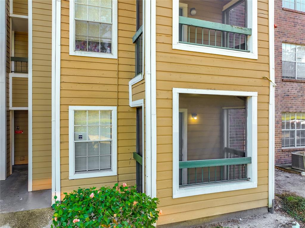 The exterior of a multi-story apartment building features yellow siding, screened balconies, and white trim — 4301 LIZSHIRE LANE UNIT 107, ORLANDO, FL