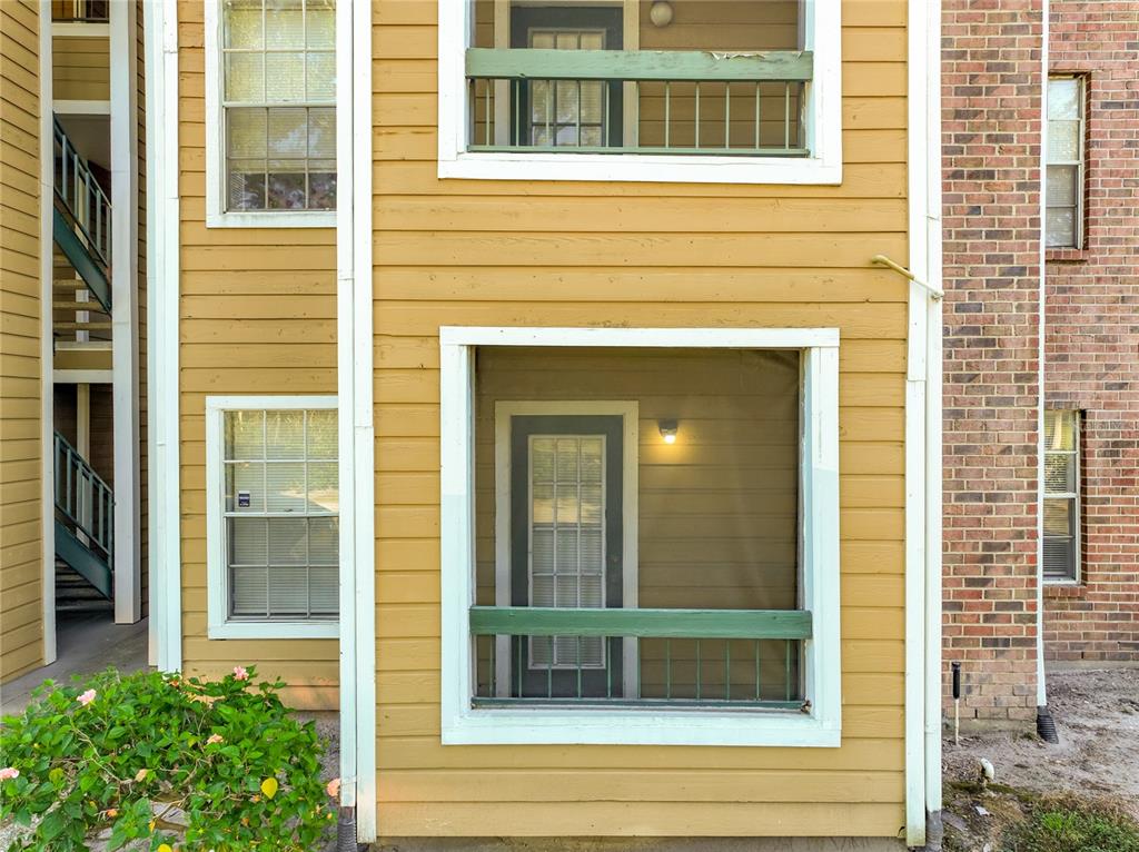 The exterior of a yellow-sided apartment building features screened-in porches and a brick section — 4301 LIZSHIRE LANE UNIT 107, ORLANDO, FL
