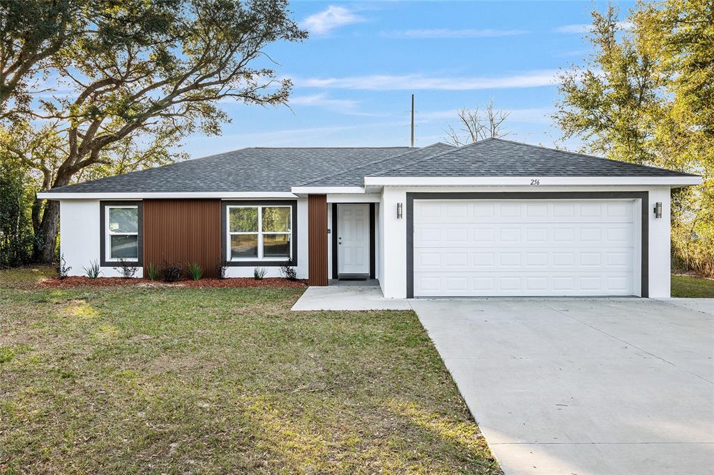 A single-story house features a white exterior, brown vertical siding, and a two-car garage — 7778 SW 146TH LANE ROAD, OCALA, FL