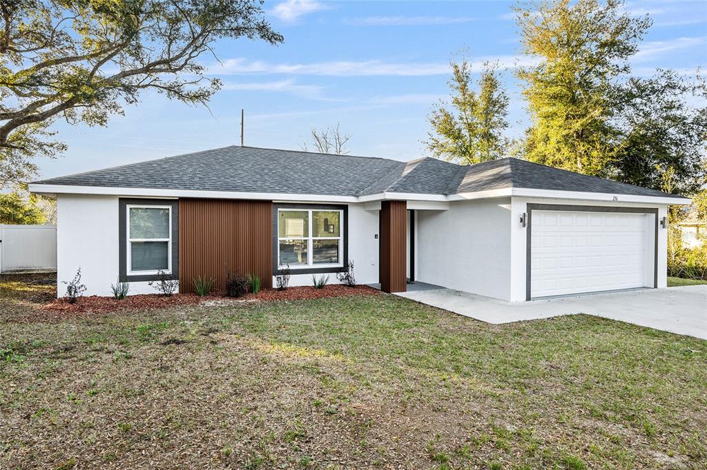 A single-story house with white stucco walls, brown vertical siding, and a two-car garage — 7778 SW 146TH LANE ROAD, OCALA, FL