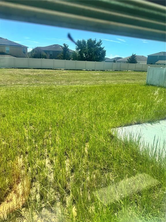 A view of a backyard with tall grass and a fence from inside a house — 487 EAGLECREST DRIVE, HAINES CITY, FL