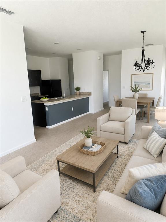 An open-concept living room and kitchen area features neutral furniture, a wooden coffee table, and carpet — 487 EAGLECREST DRIVE, HAINES CITY, FL
