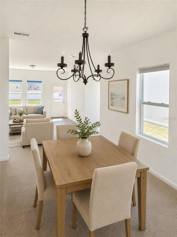 A dining area with a wooden table and chandelier opens into a living room — 487 EAGLECREST DRIVE, HAINES CITY, FL