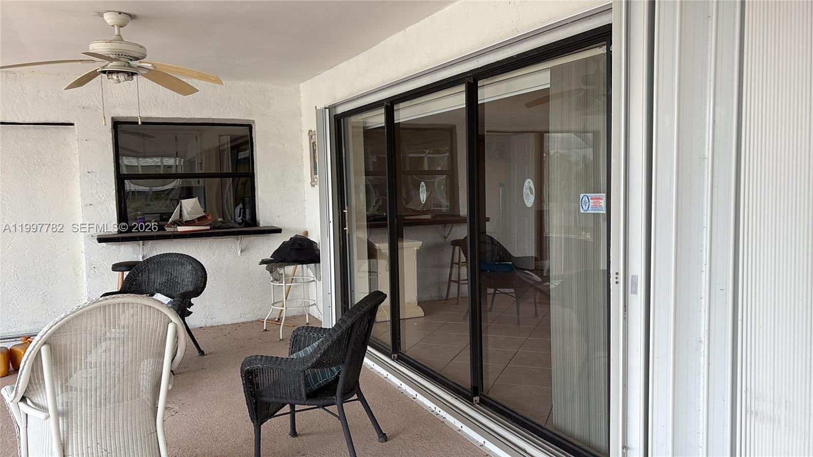 A covered patio features wicker chairs, a ceiling fan, and large sliding glass doors — 251 SW 22 Place, Cape Coral FL 33991, CAPE CORAL, FL