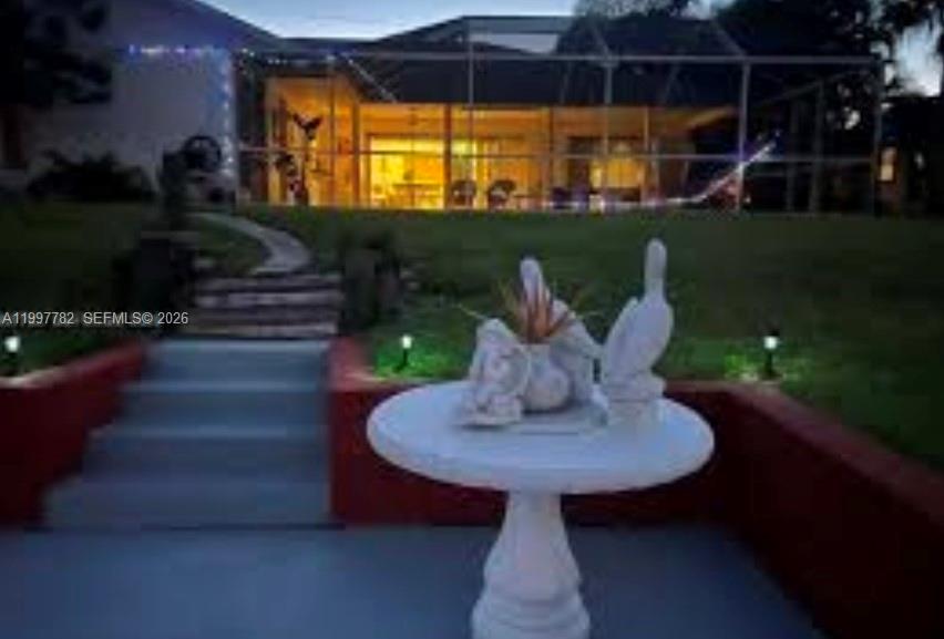 A white pedestal table with bird statues sits on a patio overlooking a screened-in house — 251 SW 22 Place, Cape Coral FL 33991, CAPE CORAL, FL