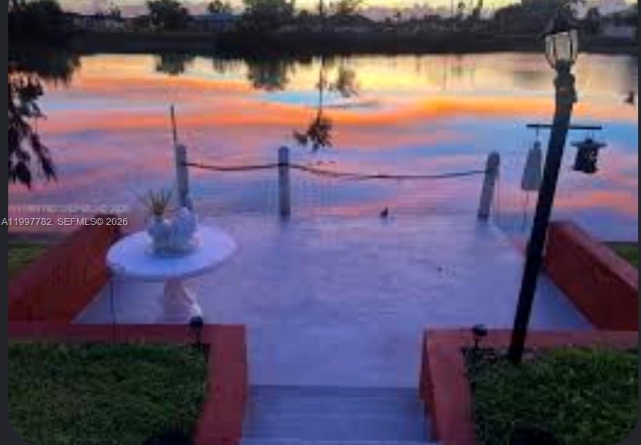 A patio with a white table overlooks a lake at sunset with a lamp post — 251 SW 22 Place, Cape Coral FL 33991, CAPE CORAL, FL