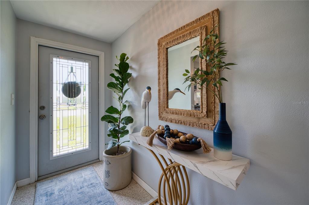 A foyer features a marble-topped console table, a mirror, a potted plant, and a door — 510 DONA DRIVE, NOKOMIS, FL