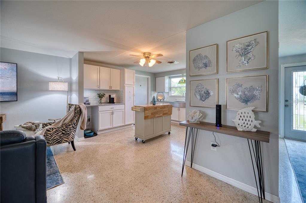 A kitchen with white cabinets and a rolling island opens into a living area — 510 DONA DRIVE, NOKOMIS, FL