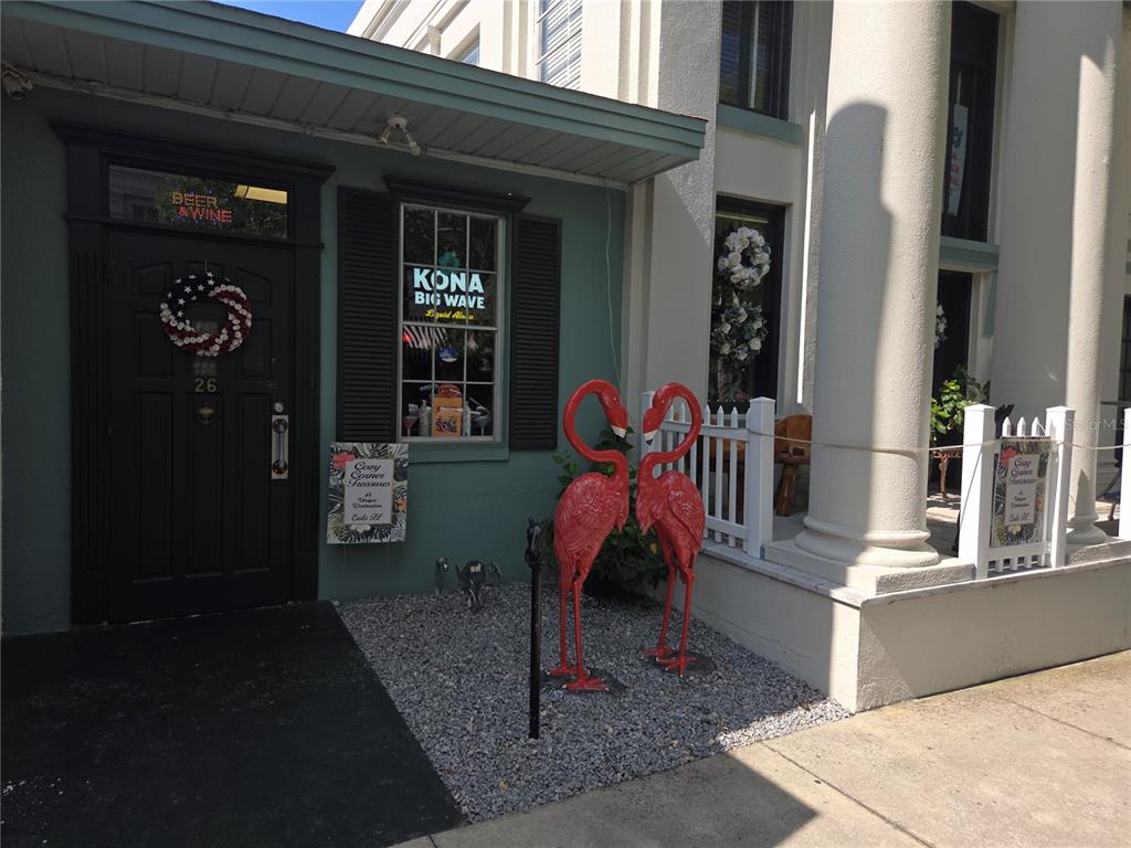 A rustic wooden bar with three stools sits in a room decorated with eclectic wall art — 30 E MAGNOLIA AVENUE, EUSTIS, FL
