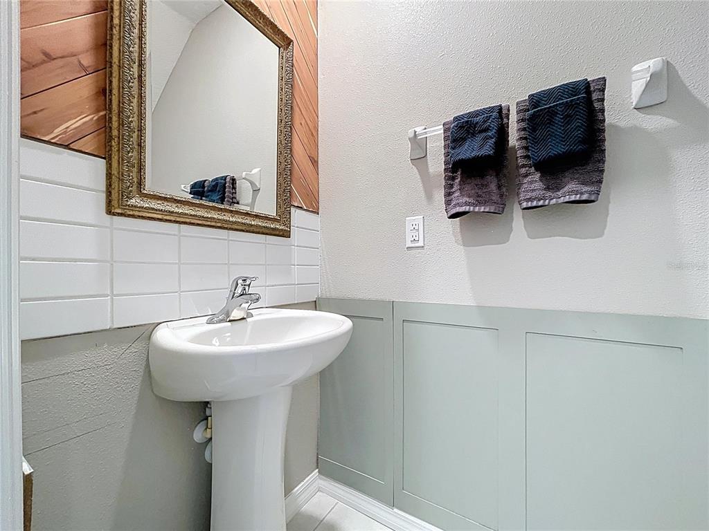 A small bathroom with green wainscoting and a toilet sits beside a tiled entryway — 3141 OYSTER COVE STREET, WIMAUMA, FL