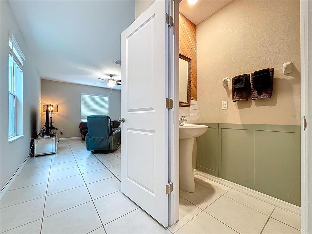 A bathroom features a pedestal sink, a framed mirror, subway tile, and light green wainscoting — 3141 OYSTER COVE STREET, WIMAUMA, FL