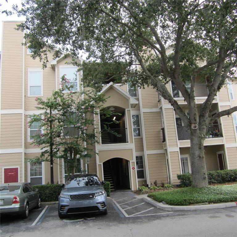 A three-story apartment building with tan siding and a parking lot in front — 1985 ERVING CIRCLE UNIT 205, OCOEE, FL