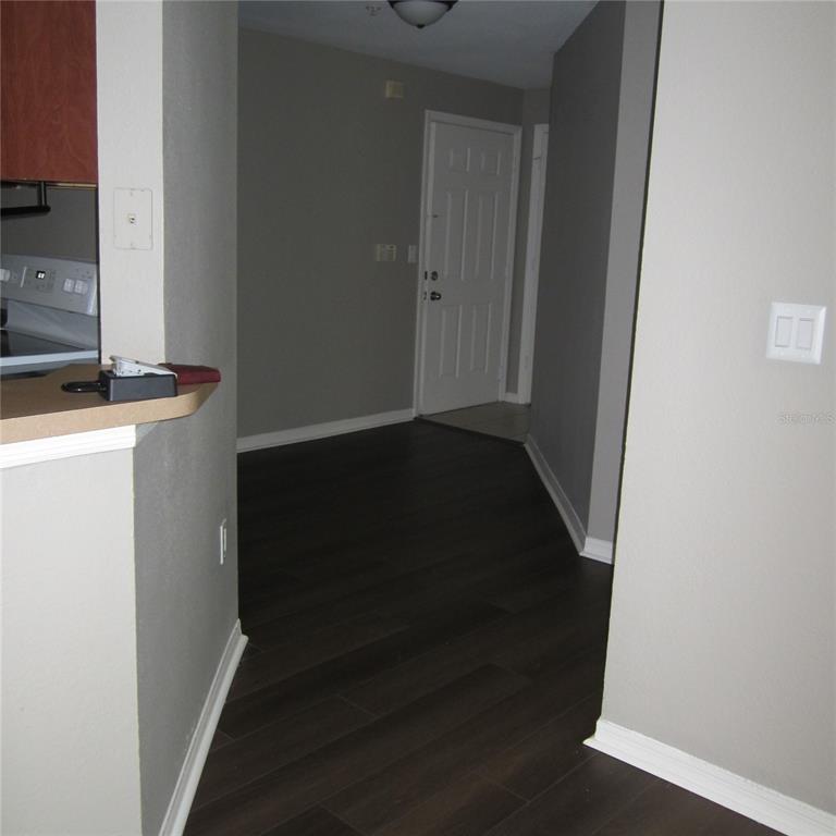 A view of a hallway with dark wood-look flooring leading to a white front door — 1985 ERVING CIRCLE UNIT 205, OCOEE, FL