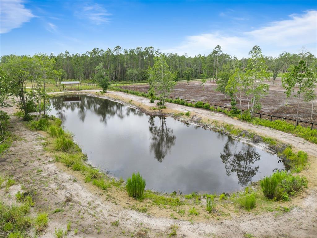 A pond sits in the foreground of a rural property with trees and a fence — 5753 RETREAT ROAD, KEYSTONE HEIGHTS, FL
