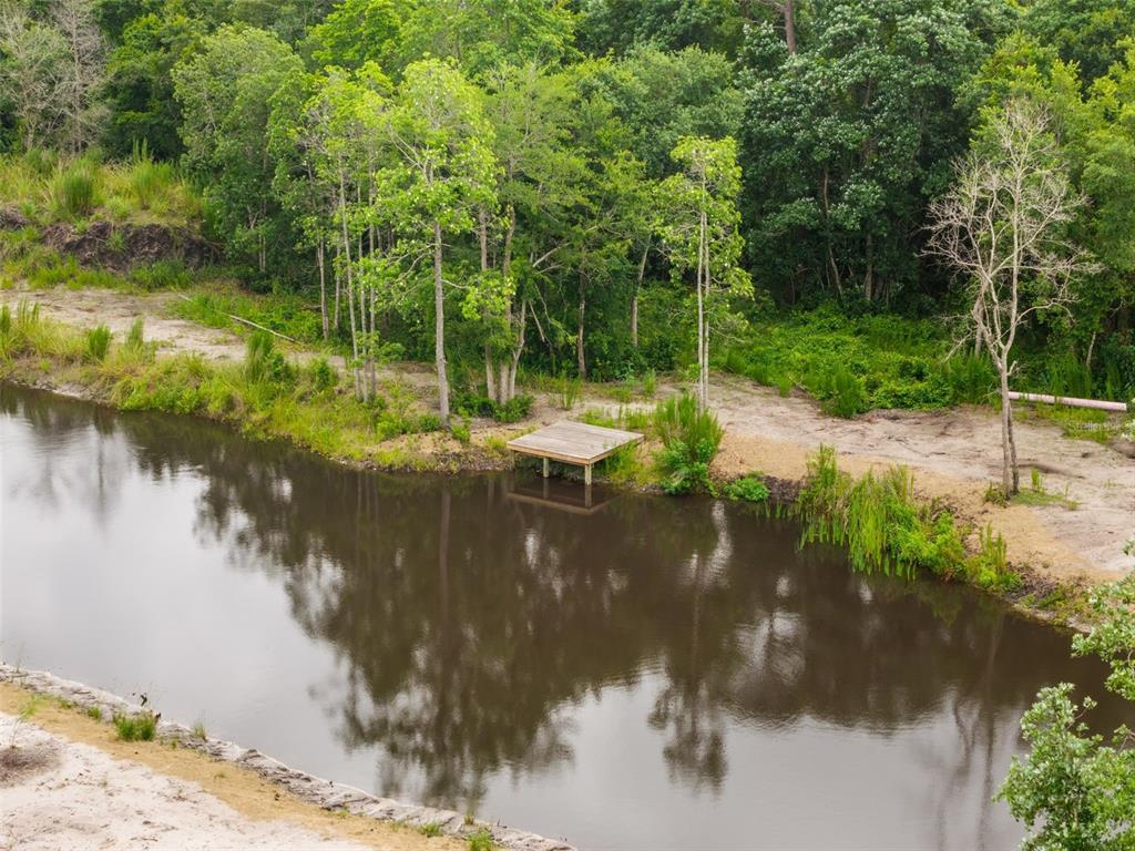 An aerial view shows a wooden deck extending over a pond near a wooded area — 5753 RETREAT ROAD, KEYSTONE HEIGHTS, FL