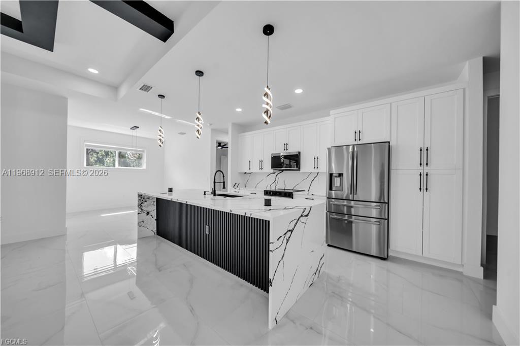 A modern kitchen features a marble-topped island with black vertical slats and white cabinetry — 7799 15th PL, La Belle FL 33935, LA BELLE, FL