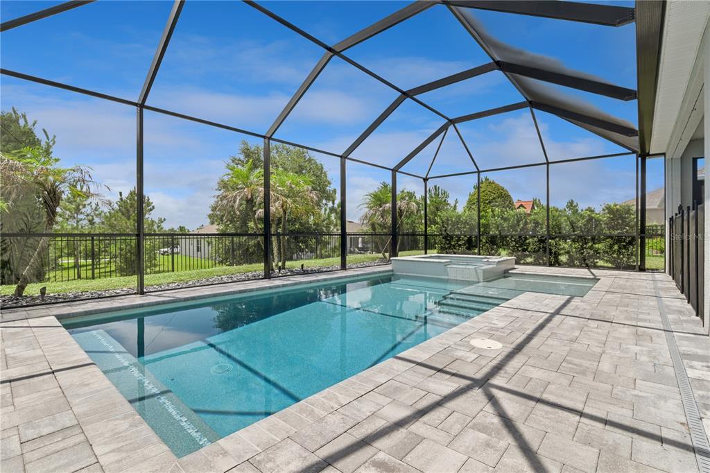 A rectangular swimming pool with an attached spa sits inside a screened-in patio enclosure — 464 WEDGEWORTH LANE, DELAND, FL