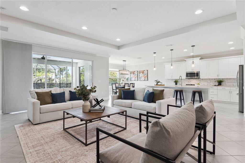 An open-concept living room and kitchen featuring white cabinetry, tile flooring, and sliding glass doors — 464 WEDGEWORTH LANE, DELAND, FL