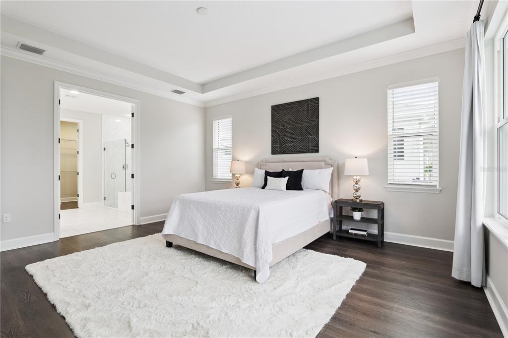 A bedroom features dark wood floors, a white rug, a bed, and an attached bathroom — 464 WEDGEWORTH LANE, DELAND, FL