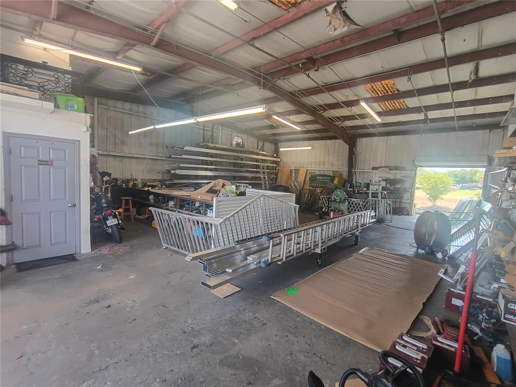 A spacious industrial workshop features a concrete floor, metal rafters, and various metal fabrication materials — 918 SE 9TH LANE, CAPE CORAL, FL