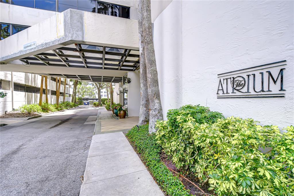 The exterior entrance of a building features a covered driveway and a sign reading The Atrium — 2413 BAYSHORE BOULEVARD UNIT 1903, TAMPA, FL