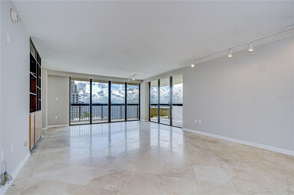 A spacious living room features light tile flooring, track lighting, and floor-to-ceiling windows with water views — 2413 BAYSHORE BOULEVARD UNIT 1903, TAMPA, FL