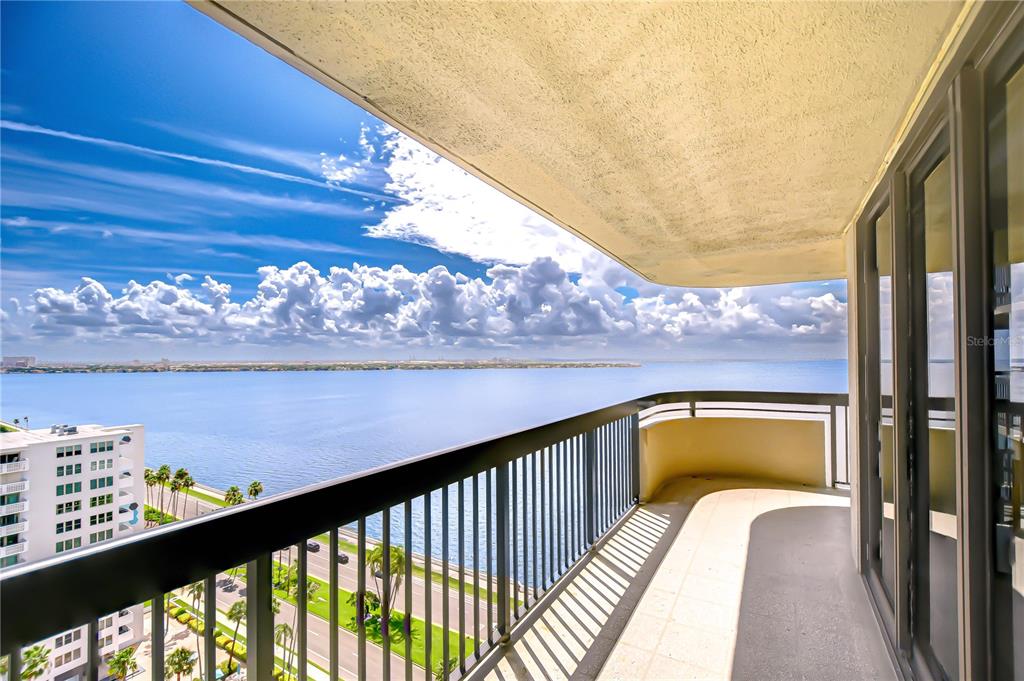 A high-rise balcony overlooks a large body of water under a bright, cloudy blue sky — 2413 BAYSHORE BOULEVARD UNIT 1903, TAMPA, FL