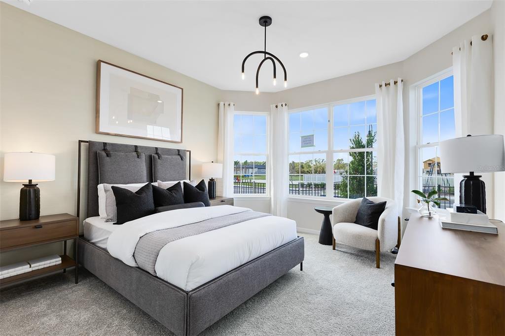 A bedroom features a gray upholstered bed, a corner armchair, and large windows with curtains — 4620 SCENIC WOODS DRIVE, CLERMONT, FL