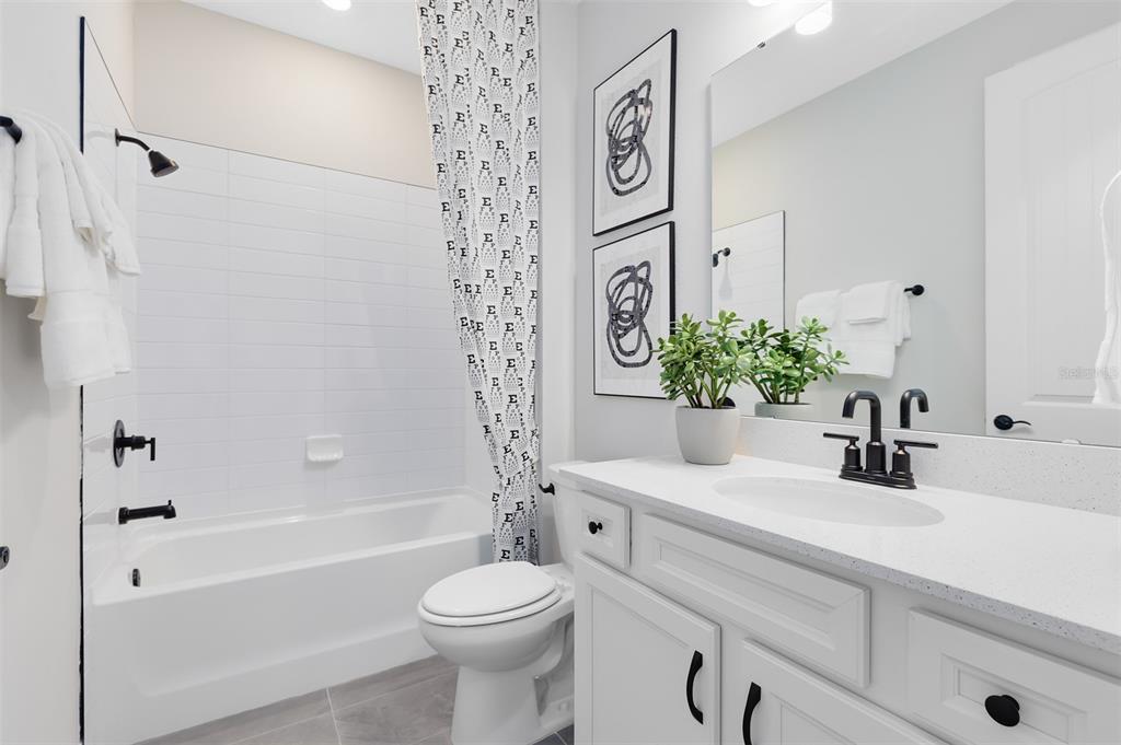 A bathroom features a white vanity, a tub-shower combination, and black hardware and accents — 4620 SCENIC WOODS DRIVE, CLERMONT, FL