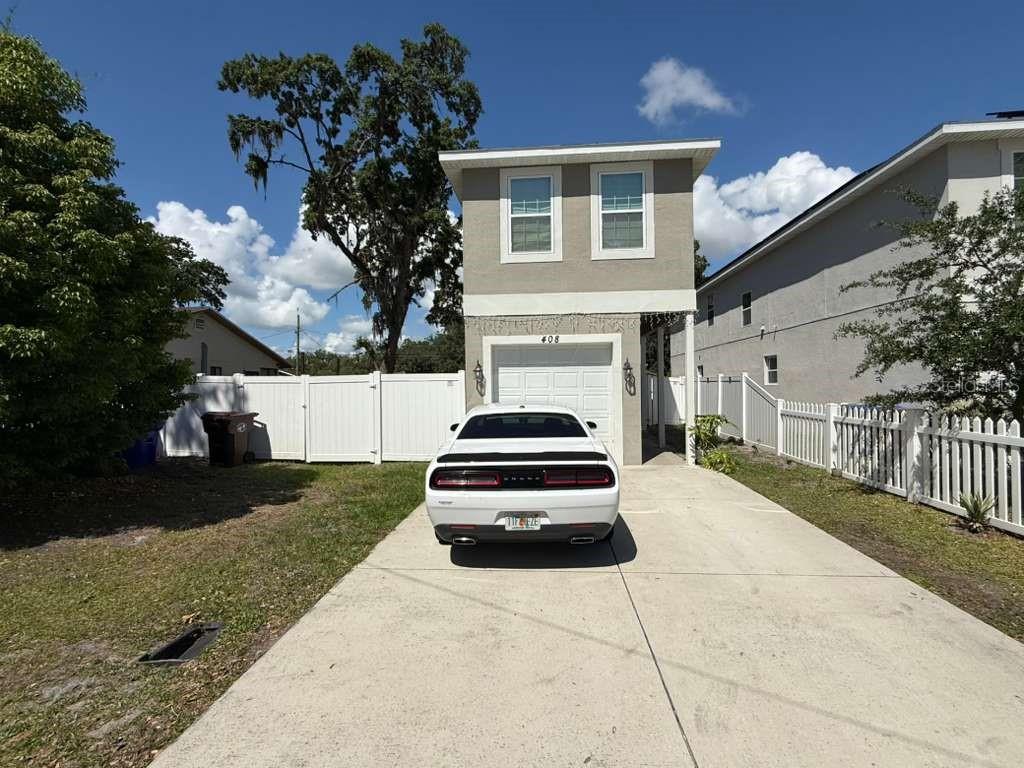A white car is parked in the driveway of a two-story house with a garage — 408 FINLEY AVENUE, KISSIMMEE, FL