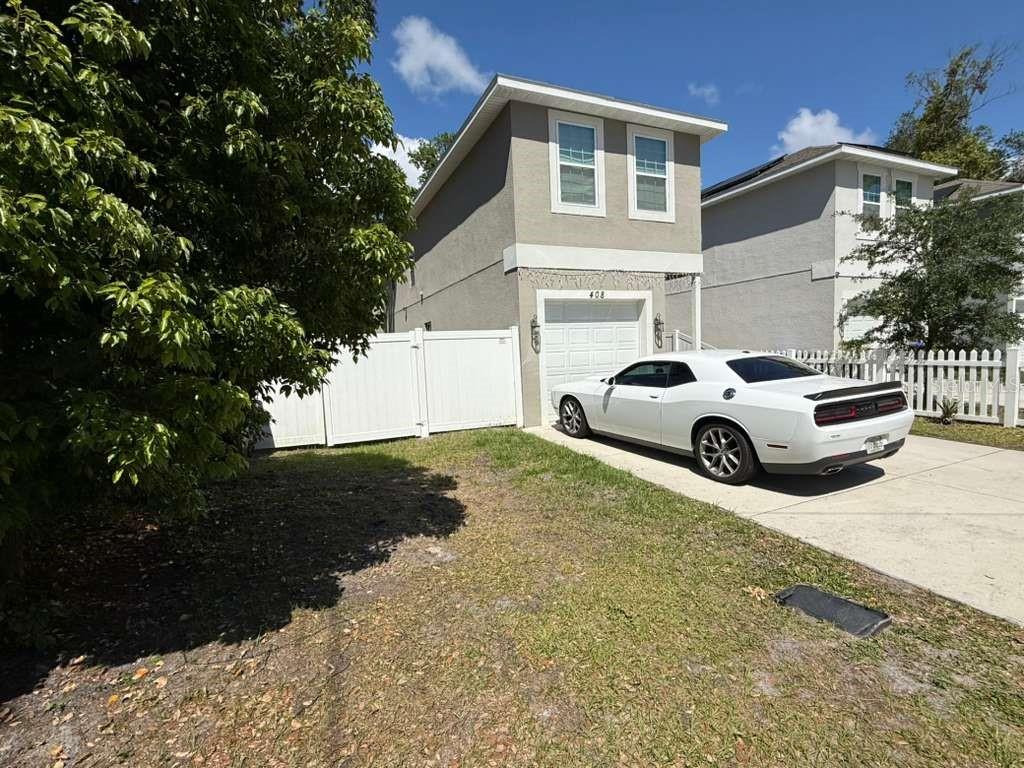 A white two-story house with a driveway and a white car parked in front — 408 FINLEY AVENUE, KISSIMMEE, FL