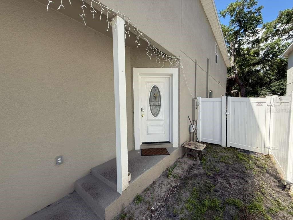 A white front door with a decorative oval window sits at the top of concrete steps — 408 FINLEY AVENUE, KISSIMMEE, FL