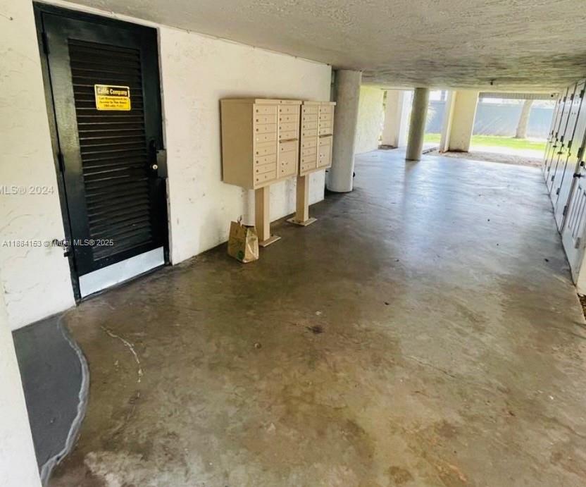 This covered outdoor area features a black door, two sets of mailboxes, and concrete flooring — 16220 NW 2nd Ave # 213, Miami FL 33169, MIAMI, FL