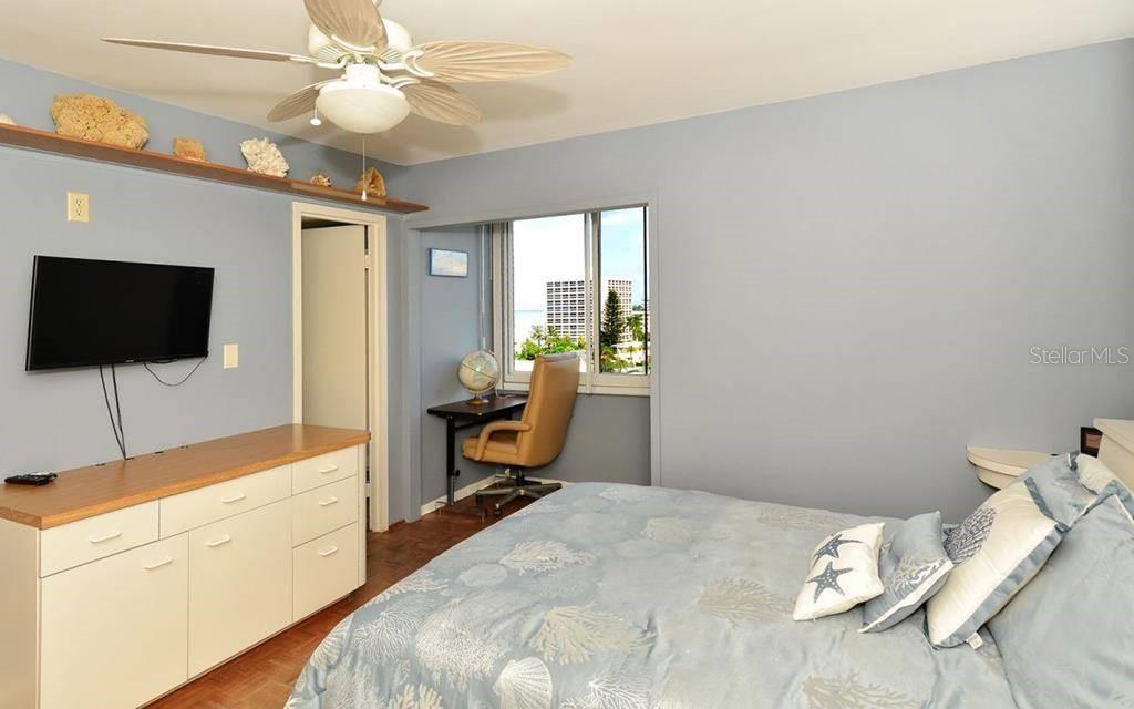 A bedroom features a light blue wall, a ceiling fan, a dresser, and a desk — 1055 W PEPPERTREE DRIVE UNIT 603AA, SARASOTA, FL