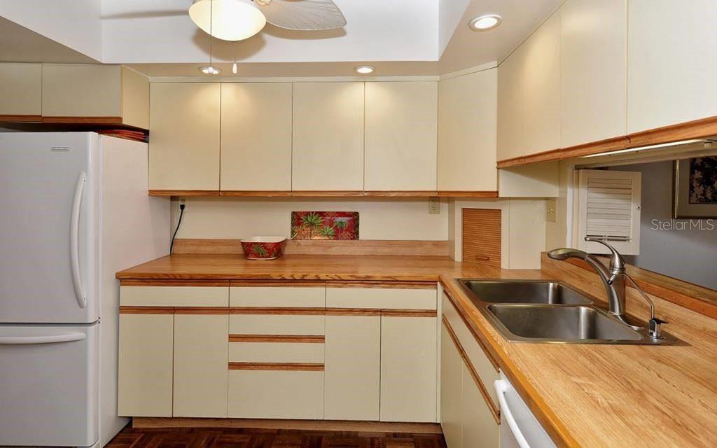 A kitchen features light-colored cabinets, wood-look countertops, a double sink, and a white refrigerator — 1055 W PEPPERTREE DRIVE UNIT 603AA, SARASOTA, FL