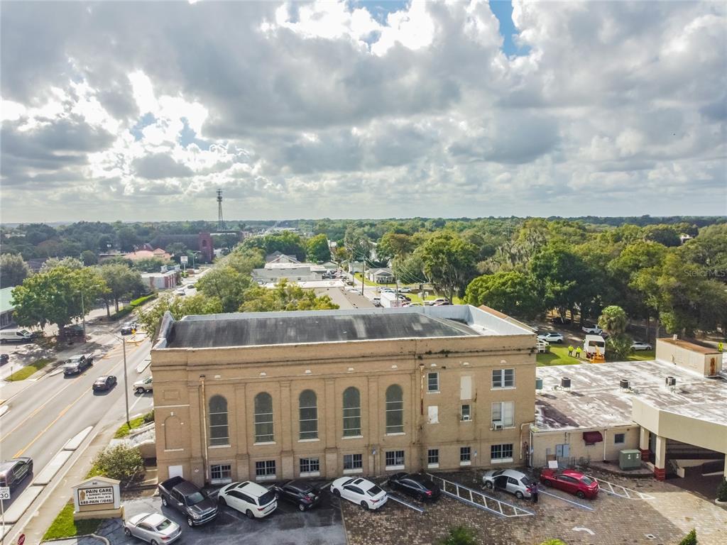 An aerial view shows a multi-story brick building with a parking lot and surrounding trees — 541 S FLORIDA AVENUE, LAKELAND, FL