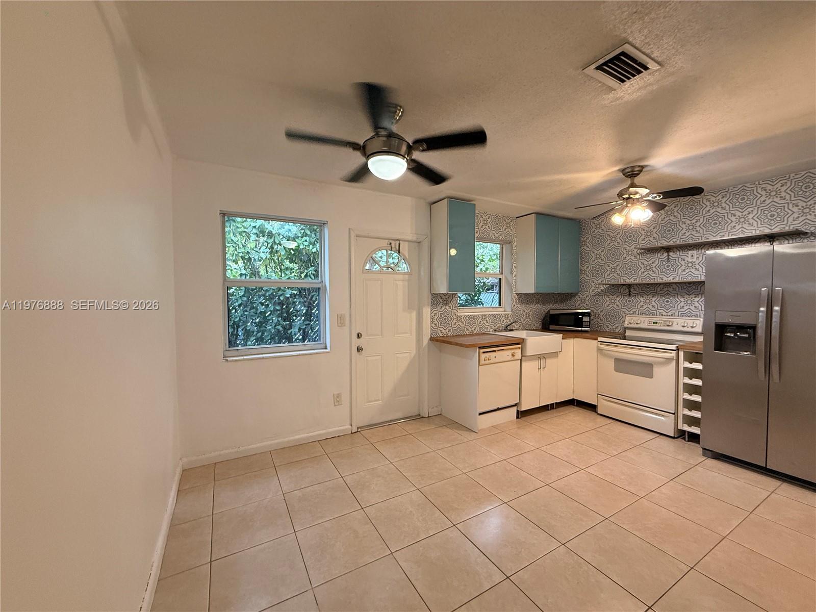A kitchen features light blue cabinets, patterned backsplash tile, stainless steel appliances, and tile flooring — 1104 N 17th Ct # 105, Hollywood FL 33020, HOLLYWOOD, FL
